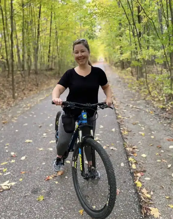 Kelly Pottage poses for a picture while on a bicycle in the forest