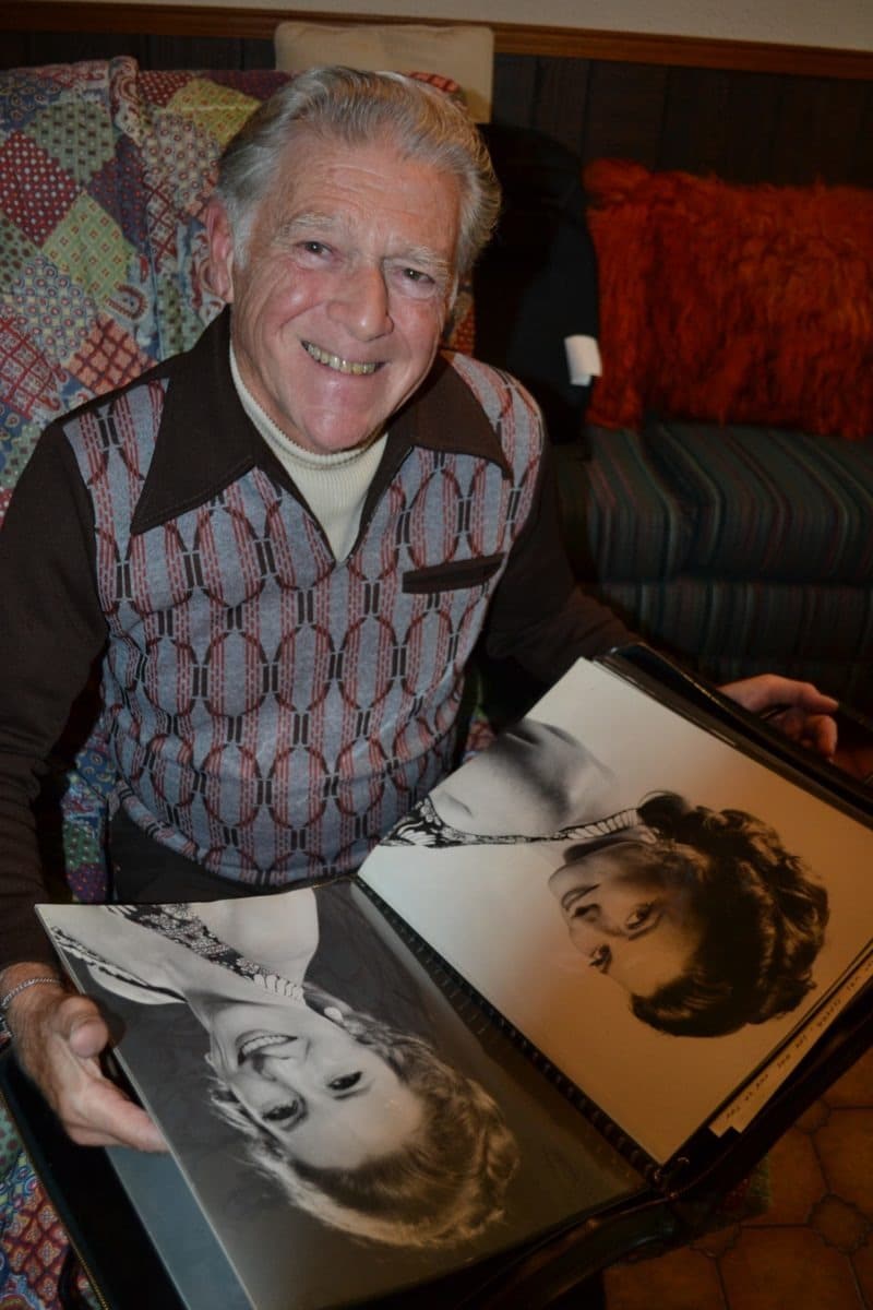 Don Saunders smiles at the camera as he flips through a photo album with beautiful black and white images of his late wife, Joni.